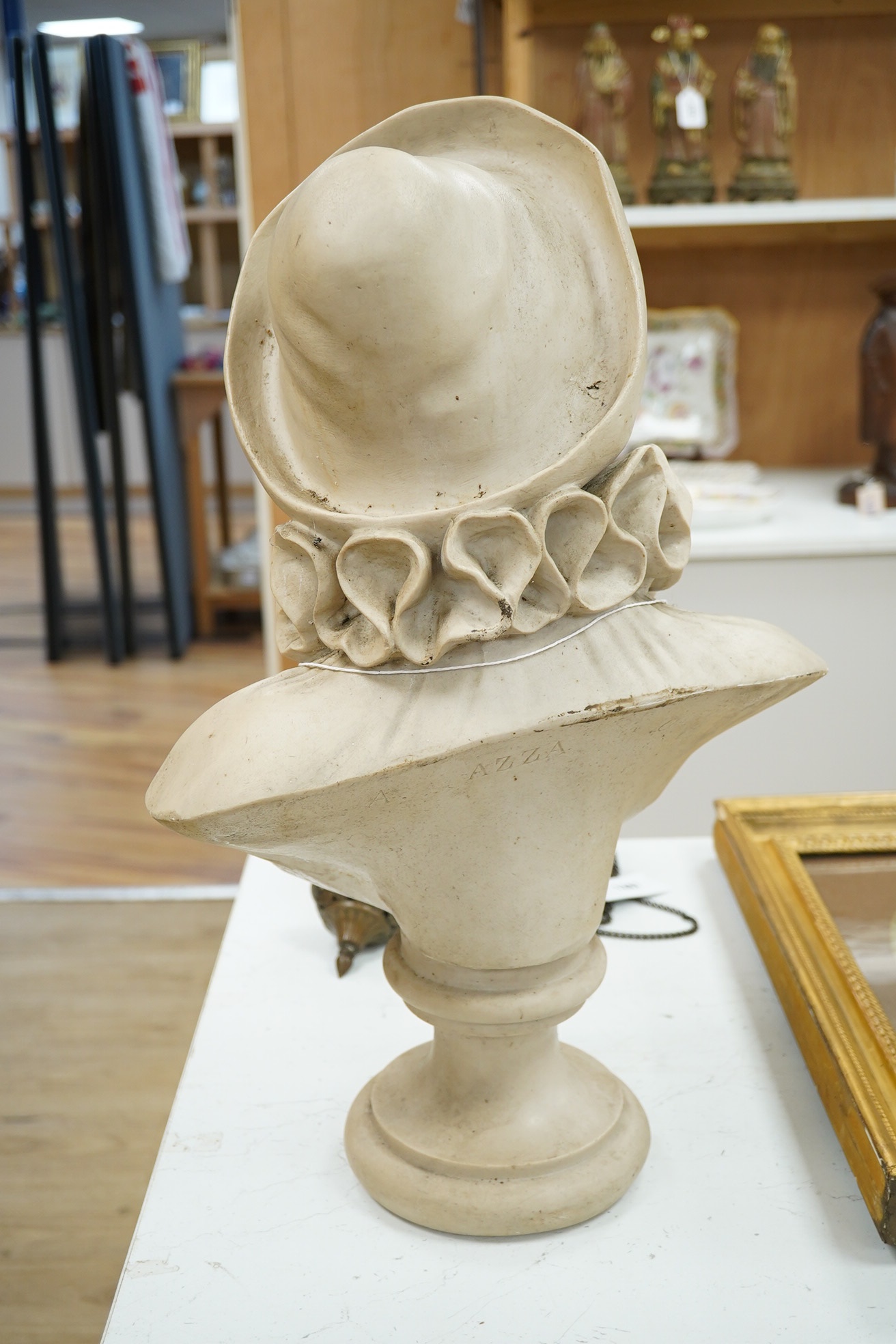 A composition bust of a boy on stand in a hat, ruff and pom-pom buttoned top, inscribed ‘A Azza’, 55cm high. Condition - fair